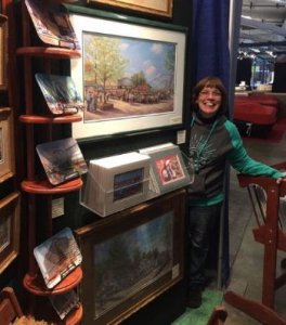 This photo features Linda Barnicott, Pittsburgh's Painter of Memories, smiling next to her booth at the Pittsburgh Home and Garden Show.