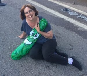 Linda Barnicott, Pittsburgh's Painter of Memories, sitting on the ground of the Clemente Bridge with a pickle balloon.