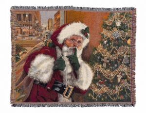 The image shows a close up of Linda Barnicott's new throw blanket featuring her painting "Shhh!" Santa Claus is holding his bag of toys while standing beside a Christmas tree.