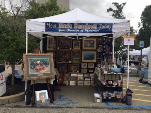 An image of Linda Barnicott's show booth with a her paintings displayed.