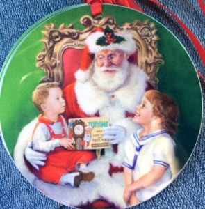 An image of Linda Barnicott's newest ornament, Wishes For Santa, featuring Santa Claus with a small boy on his lap and a young girl looking up at him.