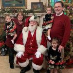 This image features Linda Barnicott, her husband, and granddaughters posing with Santa Claus.