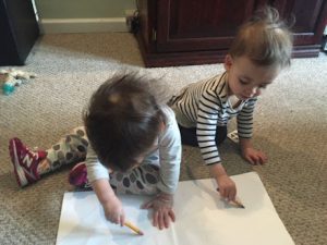 This image features Linda Barnicott's granddaughters, Abigail and Autumn (age 18 months), drawing together on a sheet of paper.