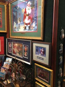 This image shows a portion of Linda Barnicott's 2020 Home & Garden Show booth, including images of her Jolly Old Elf Series (Santa's Woodland Christmas and Santa's Snowy Friends).