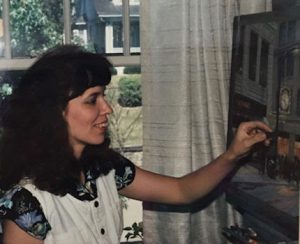 This image shows Linda Barnicott working on her painting "Meet Me Under Kaufmann's Clock."